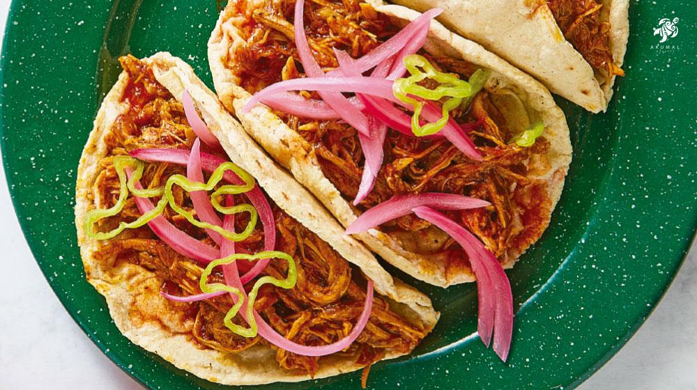 Cochinita Pibil in tacos with marinated red onions